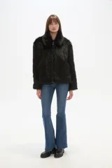 Campera de piel sintética color negro, con cuello, manga larga y cierre frontal. Presenta un diseño de corte holgado y textura suave.