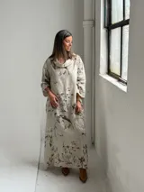 Vestido largo beige con diseño estampado de flores, cuello redondo amplio y mangas largas holgadas.