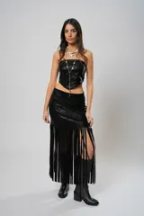 Pollera midi de cuero sintético negro, con diseño de tajo lateral y ruedo decorado con flecos largos que aportan movimiento.