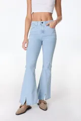 Jean azul claro de corte flare con aberturas en los tobillos y detalles rotos en las rodillas y muslos.