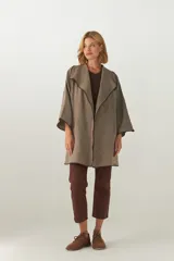 Tapado de largo medio, abierto, con cuello solapa y mangas tres cuartos. Confeccionado en lana fina sin teñir, presenta terminaciones envivadas en contraste.