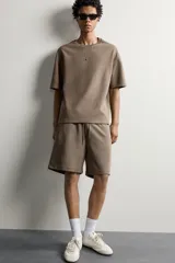 Bermuda estilo jogger de ajuste relajado, confeccionada en tejido interlock de algodón. Cuenta con cintura elástica ajustable con cordón, bolsillos frontales de vivo y diseño liso.