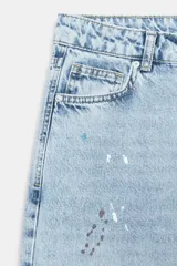 Jeans de tiro medio, corte loose straight, color celeste claro con efecto de salpicaduras de pintura en varios colores. Cierre frontal con cremallera y botón, y diseño de cinco bolsillos.