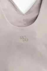 Top deportivo de sujeción media, color gris claro, con escote en V pronunciado y breteles anchos. Presenta copas forradas con relleno extraíble y elástico revestido en el bajo.