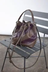 Cartera tipo botellero color marrón con efecto trenzado, tamaño mediano, cierre con frunce, correa ajustable con hebilla para usar al hombro o cruzada, doble bolsillo interior (uno con cierre).