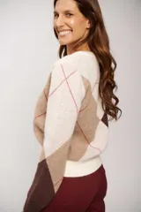 Buzo de tejido de punto con escote en V y diseño de rombos en tonos crudo, marrón y beige, con detalles de líneas finas en color rojo.