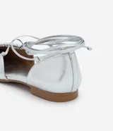 Zapatilla metalizada plateada con lazo para atar en la pierna, puntera redonda y detalle fruncido en la parte superior.
