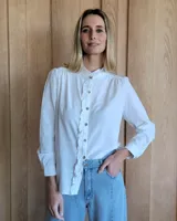 Camisa blanca de mangas largas con cuello mao y volados en el frente.