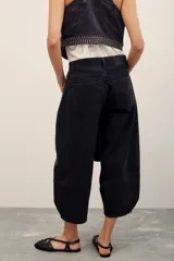 Pantalón jean negro de corte ancho y largo midi, con diseño de perneras holgadas y costuras frontales marcadas.