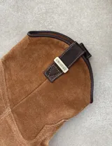 Bota corta estilo western de cuero color marrón, con taco cuadrado de 5 cm y diseño clásico. Presenta un acabado desgastado en la puntera y el talón.