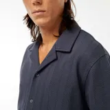 Camisa azul de manga corta con cuello cubano y cierre frontal con botones. Tejido de punto calado con diseño de espiga.