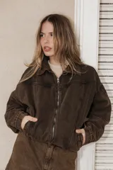 Campera de jean en color marrón chocolate con efecto lavado, corte semi oversized, cierre frontal metálico, cuello clásico y bolsillos laterales.