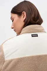 Campera de sherpa doble faz en color crema con detalles en verde oliva. Presenta cierre frontal con botones, bolsillos laterales de nylon capitoneado y terminaciones en contratono. Diseño de calce relajado con bordado en la manga.