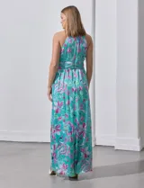 Vestido largo de gasa con estampado floral en tonos turquesa, rosa y verde. Tiene cuello halter cruzado, corte en la cintura con faja plisada y abertura en la espalda con cierre invisible.