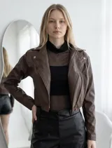 Campera de estilo biker en color chocolate, confeccionada en material engomado. Presenta solapas clásicas, cierre frontal cruzado con cremallera metálica y detalles de botones a presión en el cuello.