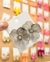 Par de aros colgantes plateados con forma de flor calada y centro con strass.