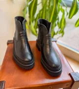 Botas de cuero negro con caña baja y suela track.