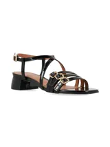 Sandalias Celeste de taco bajo y ancho, confeccionadas en cuero charol negro. Presentan múltiples tiras delgadas cruzadas sobre el empeine y tres hebillas metálicas decorativas en la parte frontal.