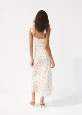 Vestido midi de viscosa color beige con estampado de flores azules, escote en V con volantes y tirantes finos ajustables.