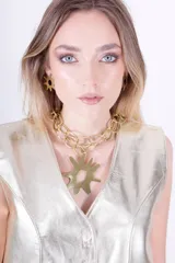 Collar dorado con cadena gruesa de eslabones y dije en forma de sol con abertura circular en el centro. Incluye aros colgantes haciendo juego.