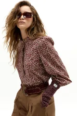 Camisa de algodón con estampado floral, cuello mao y cierre frontal con botones de nácar. Presenta mangas largas abullonadas con puños elásticos y detalle de volado en la cartera de botones.