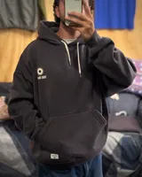 Canguro oversized color negro con estampado frontal en blanco que incluye dos soles y el texto "TRIBU BRAND".