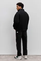 Buzo de cuello alto con cierre frontal parcial, de corte holgado y diseño minimalista con pequeño estampado central en el pecho.