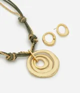 Conjunto de bisutería compuesto por un collar de hilo encerado verde con detalles de cadena metálica dorada y nudos, con un dije central de círculos concéntricos irregulares. Incluye un par de caravanas a juego con diseño circular orgánico.