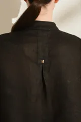 Blusa negra de lino de silueta amplia, con cuello mao y doble hilera de botones dorados en el frente. Cuenta con mangas cortas con vuelta.