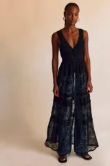 Vestido largo negro de encaje calado, sin mangas, con escote en V, fruncido en el torso y falda larga con transparencias y diseño abierto al frente.