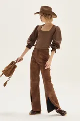 Pantalón wide leg de cuero sintético color marrón, con tajo frontal en el ruedo y cierre de botón y cremallera.