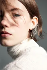 Saco de punto suave color crema, de manga corta y cuello redondo. Presenta cierre frontal con botones forrados y una moña decorativa de organza transparente en el escote. Posee terminaciones acanaladas en puños y ruedo.