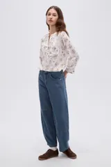 Blusa de viscosa blanca con estampado floreado en tonos marrones y amarillos, escote en V con cuello mao y manga larga.