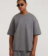 Remera gris de corte amplio, con cuello redondo y mangas cortas con dobladillo.