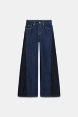 Jeans de tiro alto con pernera ancha y diseño combinado en dos tonos de denim. El panel central es de un lavado azul medio, mientras que los paneles laterales son de un lavado azul oscuro. Presenta cinco bolsillos y cierre frontal con cremallera y botón.