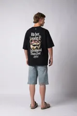 Remera de corte oversize color gris oscuro, confeccionada en algodón premium de alto gramaje. Presenta un diseño minimalista con un pequeño estampado frontal que incluye un oso y el texto 'Richer & Louder VCP'.