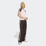 Remera Adidas de ajuste ceñido, color rosa claro con mangas y cuello en color marrón oscuro. Presenta las icónicas tres rayas de la marca en las mangas y el logo del trébol bordado en el pecho.