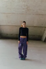 Jean de corte oversized y tiro medio-alto, confeccionado en denim de color violeta con diseño de cinco bolsillos y cierre frontal con botón y cremallera.