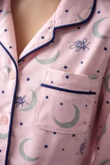 Pijama de algodón estampado con diseño de lunas y estrellas, compuesto por una camisa de manga corta abotonada y un short con cordón ajustable en la cintura.