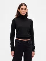 Buzo de punto fino con cuello alto tipo polera, de corte ajustado y manga larga con puños acanalados.