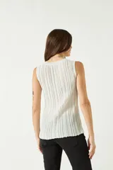 Musculosa de punto acanalado en color beige con acabado brillante, de corte al cuerpo y cuello redondo.