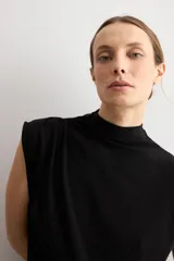 Blusa de lurex negra sin mangas, con cuello alto drapeado y detalle de pliegues frontales.