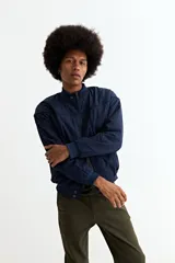 Campera tipo bomber de color azul marino, confeccionada en nylon, con cierre frontal, cuello tipo mao y puños elásticos.