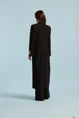 Tapado negro Natalia Antolín modelo Lavanda, de corte largo y silueta envolvente, con solapas amplias y etiqueta con la marca estampada en el puño.
