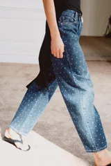 Jeans de tiro medio con corte tapered y largo al tobillo. Presenta un diseño de cinco bolsillos, cierre frontal con cremallera y botón, y un estampado de lunares a contraste sobre un tejido denim con efecto lavado.