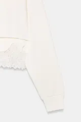 Sudadera crop de cuello redondo y manga larga con puños elásticos. Presenta un diseño de doble capa con un top interior satinado y un bajo decorado con encaje a tono.