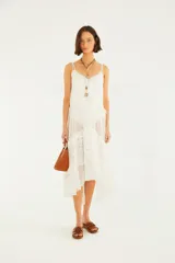 Vestido midi blanco de tirantes dobles, confeccionado con paños de tul plumeti y encaje floral. Presenta escote en V, forro corto interno, volados y un ruedo asimétrico con transparencias.
