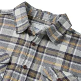 Camisa de franela a cuadros color blanco, gris y ocre, de manga larga, con cuello clásico, cierre frontal con botones y dos bolsillos con solapa abotonada en el pecho.