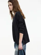 Sweater negro de hilo con textura brillosa, escote en V y manga larga.