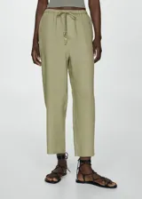 Pantalon de lino color verde oliva, con diseño crop y corte jogger. Presenta cintura elástica con cordón ajustable, bolsillos laterales y bolsillos de ribete en la parte posterior.